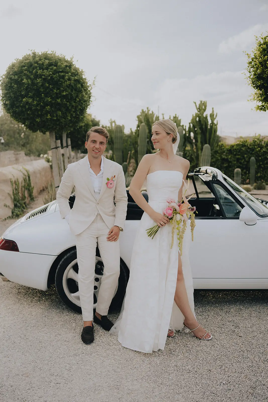 Lena und Fabian vor einem weißen Cabrio im Garten des Cal Reiet