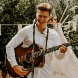 DJ Hochzeit Hochzeits-DJ Ein Mann spielt eine Akustikgitarre vor einem Tipi bei einer Hochzeit-DJ-Veranstaltung in Düsseldorf, Ruhrgebiet.