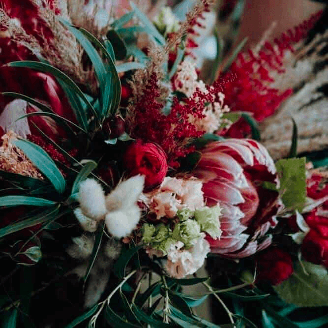 DJ Hochzeit Hochzeits-DJ Ein atemberaubender Strauß aus leuchtend roten Blumen und üppigem Grün, perfekt für eine romantische Hochzeit.