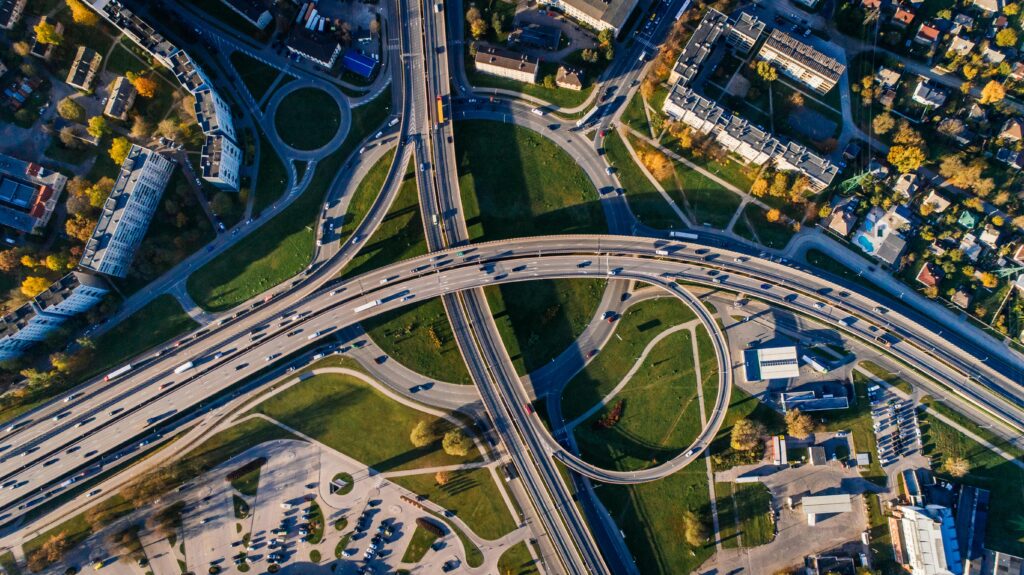 DJ Hochzeit Hochzeits-DJ Luftaufnahme eines komplexen Autobahnkreuzes mit mehreren Schleifenstraßen, umgeben von Gebäuden und Grünflächen.